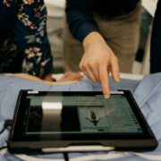 two people working on tablet at hospital bed representing tough HIPAA password requirements in the healthcare sector